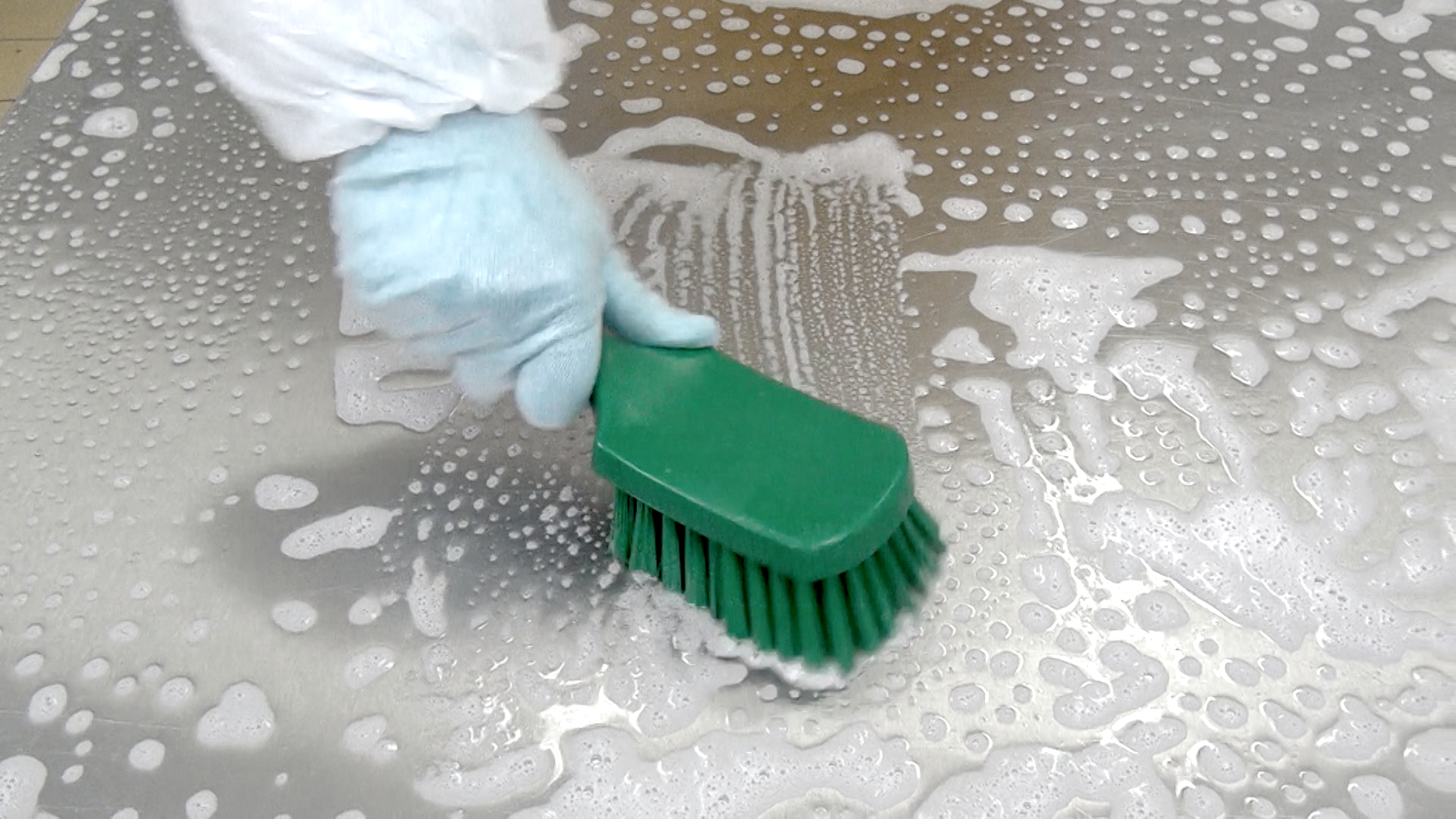 Easy Sanitization en person, der rengør en overflade med en grøn børste