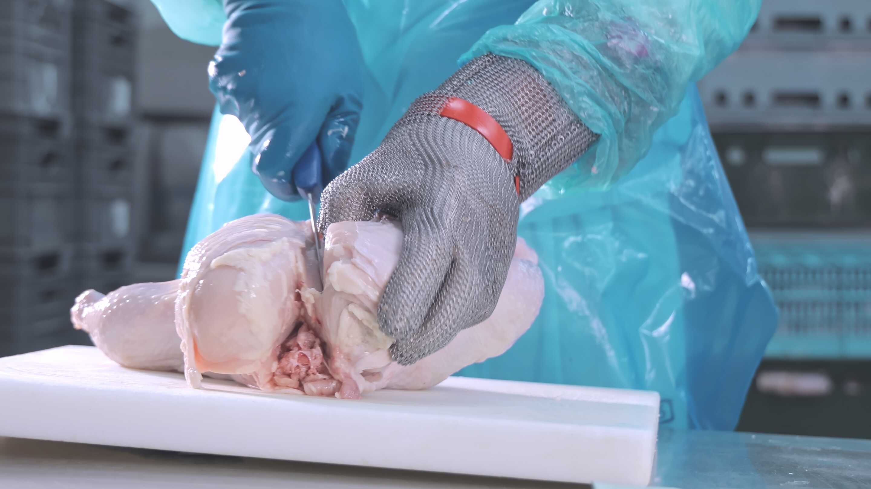 Opérationnalité avec des gants une personne découpant un poulet