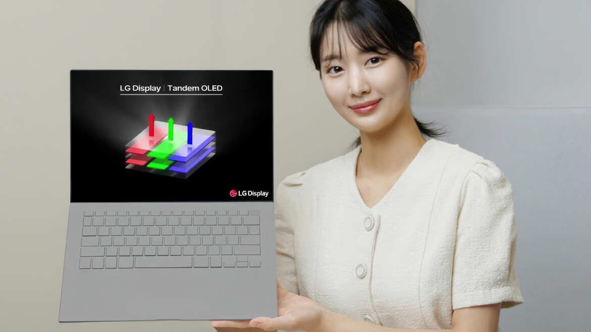 LG memperkenalkan Tandem OLED seorang wanita yang sedang memegang laptop