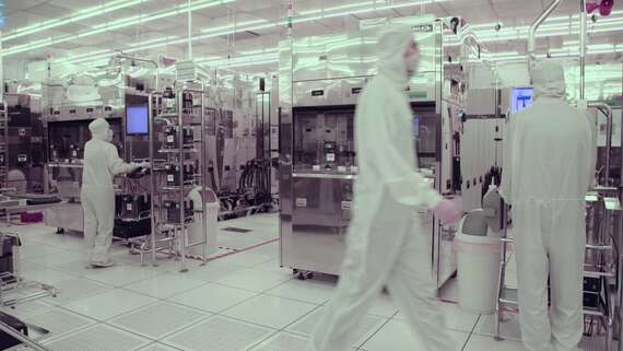 Industriële Monitor - Skoonkamer vergadering 'n man in 'n wit pak wat in 'n fabriek loop